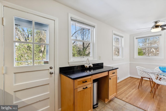 interior space featuring dark stone countertops, light tile patterned flooring, ceiling fan, and a wealth of natural light