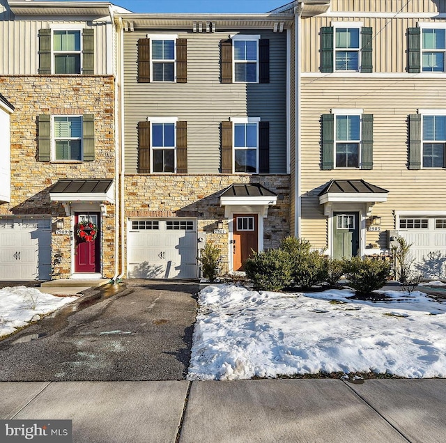 multi unit property with an attached garage, stone siding, driveway, and board and batten siding