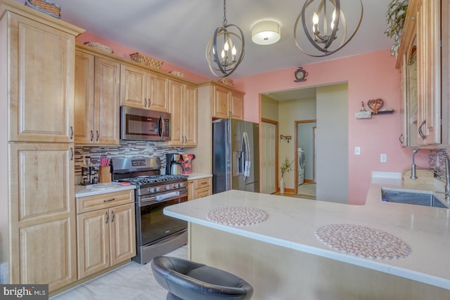 kitchen featuring decorative light fixtures, a notable chandelier, kitchen peninsula, sink, and stainless steel appliances