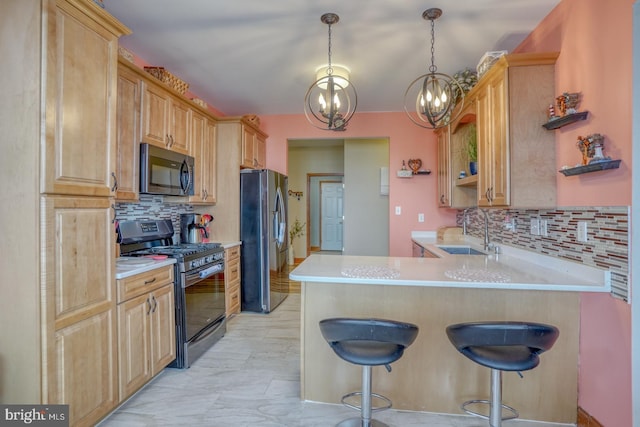 kitchen with appliances with stainless steel finishes, a kitchen bar, sink, kitchen peninsula, and a chandelier