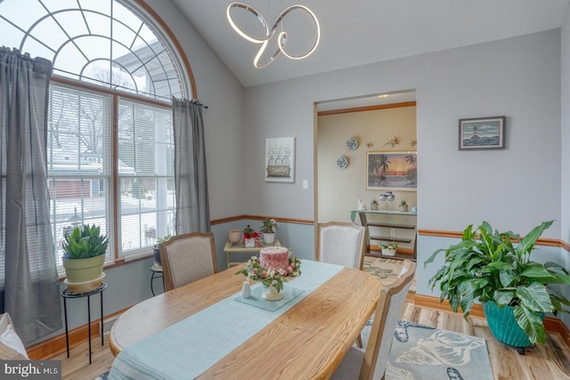 dining area featuring light wood-type flooring, vaulted ceiling, and a chandelier