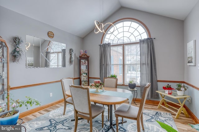 dining area with lofted ceiling, a notable chandelier, and light hardwood / wood-style floors