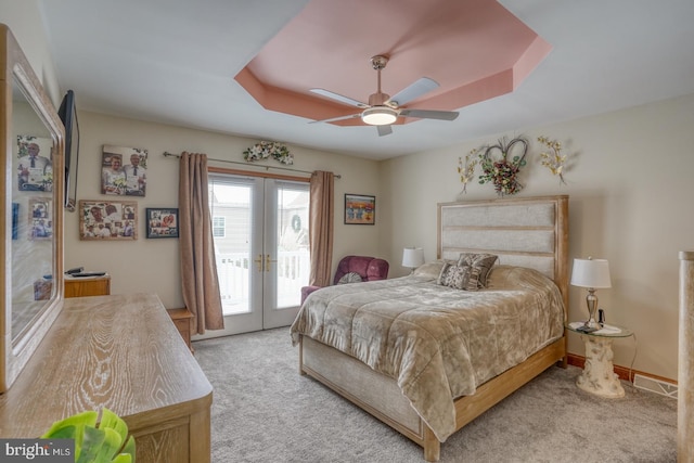 bedroom featuring french doors, access to exterior, a raised ceiling, ceiling fan, and light colored carpet