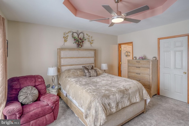 bedroom with ceiling fan, a raised ceiling, and light carpet