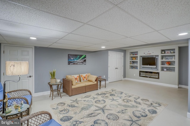 living room with concrete floors, built in features, and a paneled ceiling