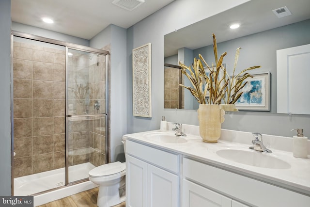 bathroom featuring hardwood / wood-style flooring, a shower with door, vanity, and toilet