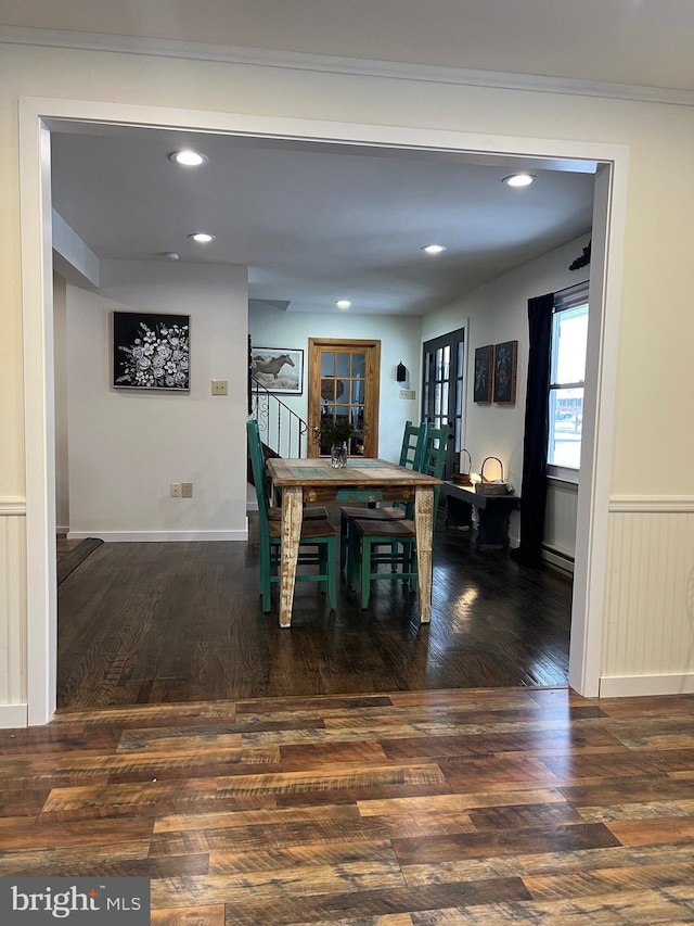 dining room with dark wood-type flooring, baseboard heating, and crown molding