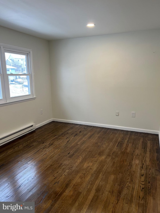 unfurnished room with dark hardwood / wood-style floors and a baseboard radiator