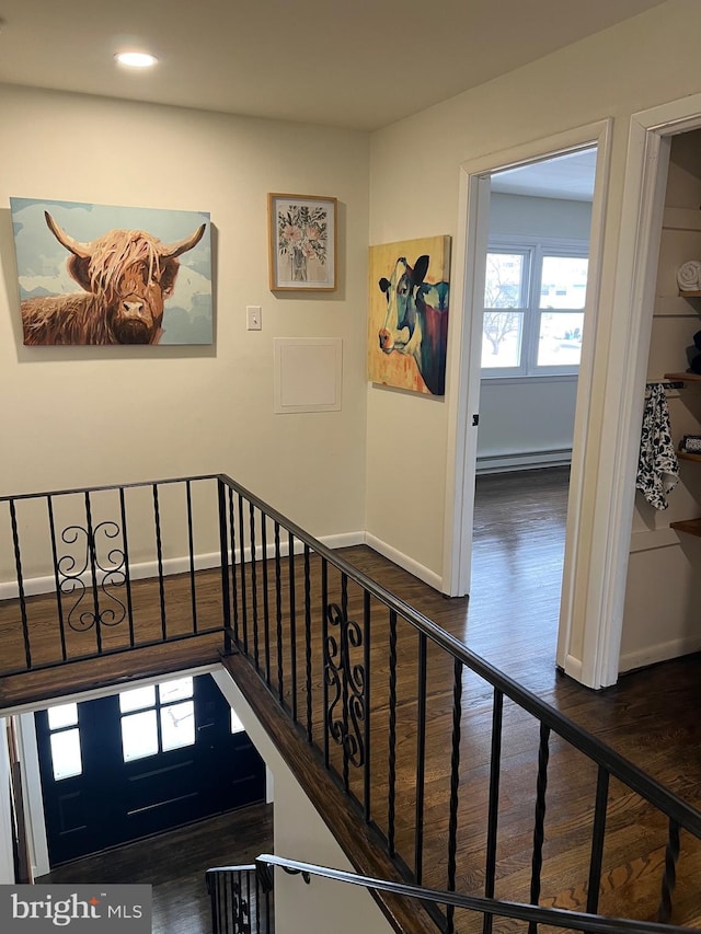 stairway featuring hardwood / wood-style floors and a baseboard heating unit