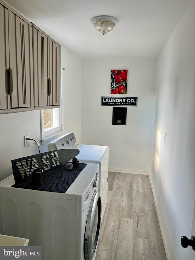 laundry room with cabinets, light hardwood / wood-style floors, and washer and clothes dryer