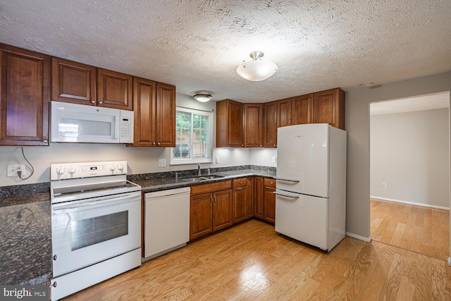 9416 Mirror Pond Dr, Fairfax, VA 22032 - kitchen with white appliances, light wood-style flooring, a textured ceiling, brown cabinets, and dark stone countertops