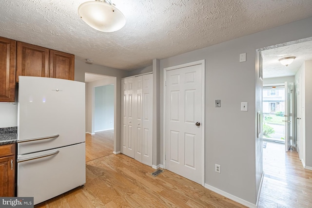 9416 Mirror Pond Dr, Fairfax, VA 22032 - kitchen with freestanding refrigerator, light wood finished floors, brown cabinetry, and a textured ceiling