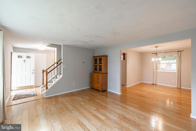 9416 Mirror Pond Dr, Fairfax, VA 22032 - unfurnished living room with a textured ceiling, light wood-style flooring, stairway, and a chandelier