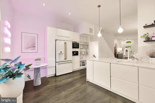 kitchen with sink, white cabinetry, light stone countertops, decorative light fixtures, and built in fridge