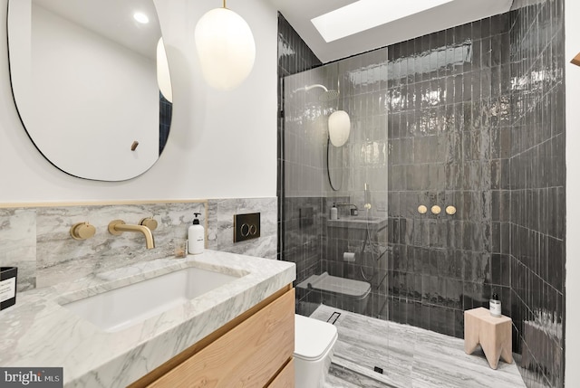 bathroom featuring toilet, a skylight, tile walls, a tile shower, and vanity