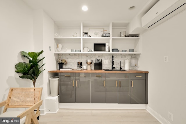 bar featuring gray cabinets, tasteful backsplash, an AC wall unit, and sink