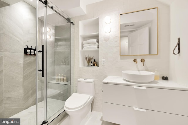 bathroom with vanity, toilet, a shower with door, and tile walls