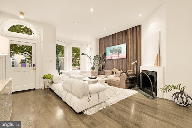 living room featuring a tiled fireplace, plenty of natural light, and dark hardwood / wood-style floors