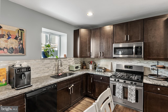 kitchen featuring sink, light stone counters, tasteful backsplash, light hardwood / wood-style flooring, and appliances with stainless steel finishes