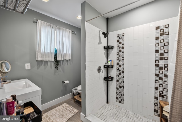 bathroom with hardwood / wood-style floors, vanity, a tile shower, and toilet