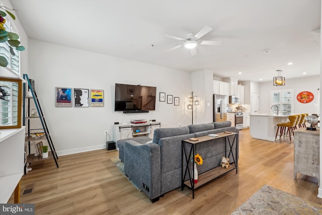 living room with sink, ceiling fan, and light wood-type flooring