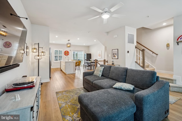 living room featuring ceiling fan, sink, and light hardwood / wood-style flooring