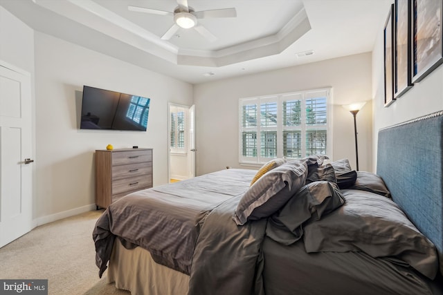 carpeted bedroom with a raised ceiling and ceiling fan