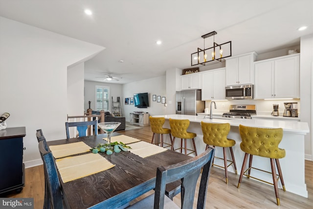 dining area featuring ceiling fan, sink, and light hardwood / wood-style flooring