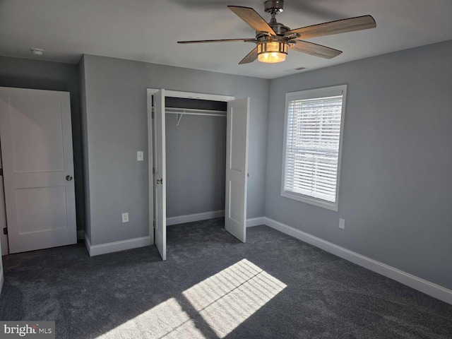 unfurnished bedroom featuring ceiling fan, dark carpet, and a closet