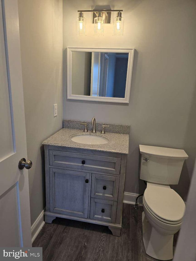 bathroom with hardwood / wood-style floors, vanity, and toilet