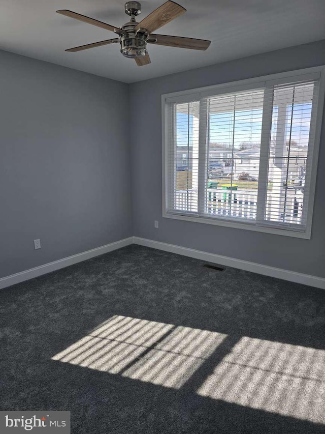 unfurnished room with dark colored carpet and ceiling fan