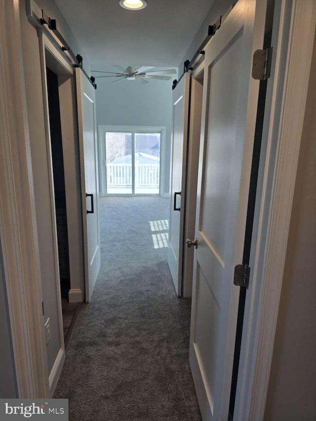 hallway with carpet flooring and a barn door