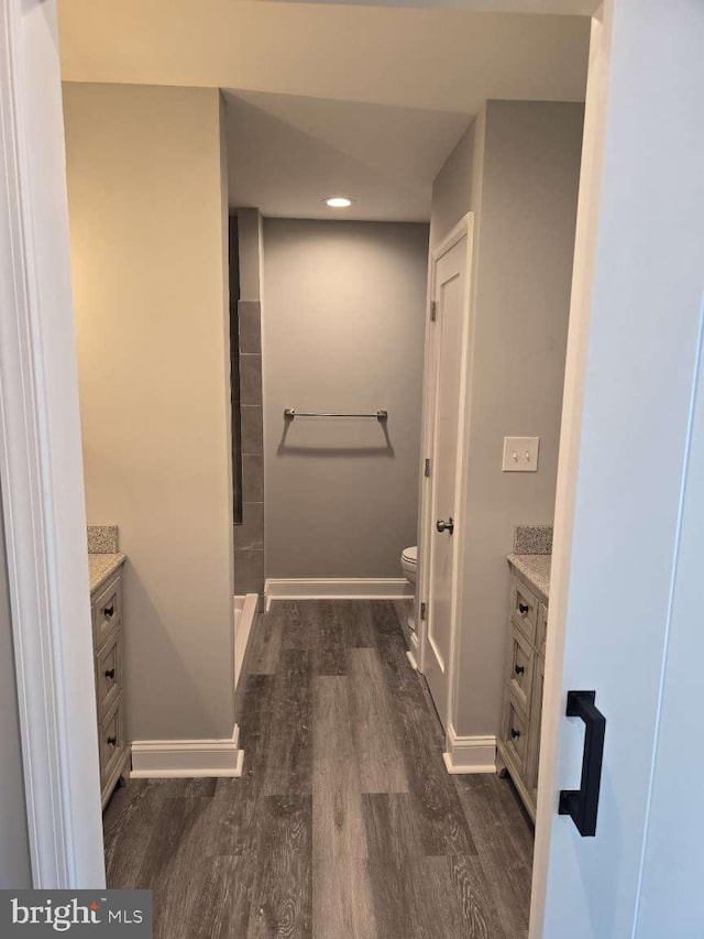 bathroom featuring hardwood / wood-style floors, vanity, toilet, and walk in shower