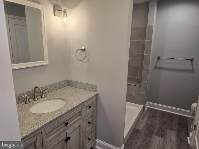 bathroom featuring a shower, hardwood / wood-style floors, vanity, and toilet