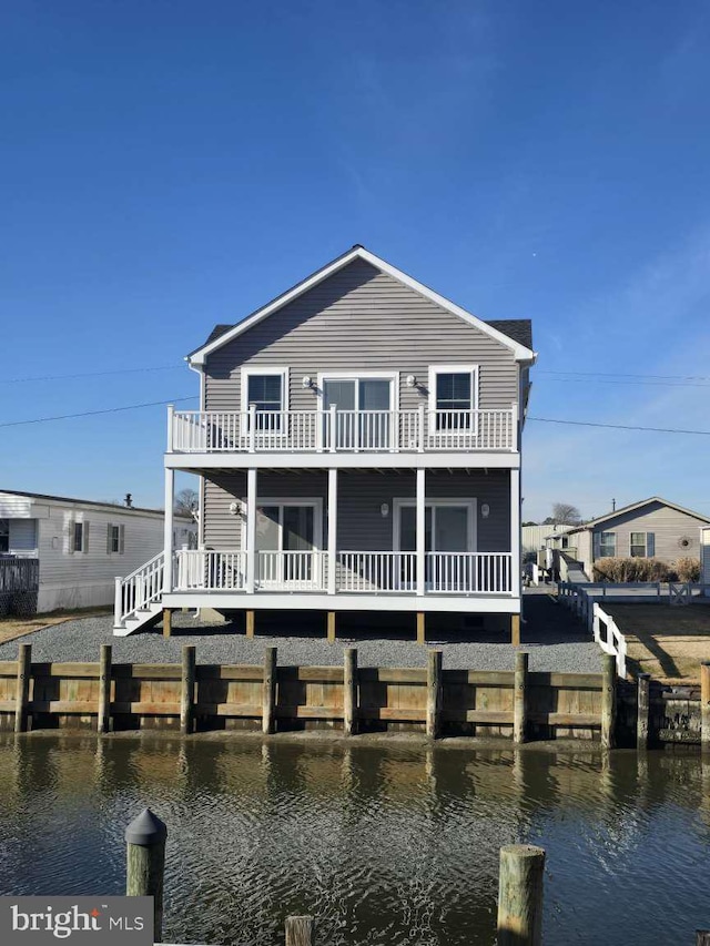 back of property with a balcony and a deck with water view