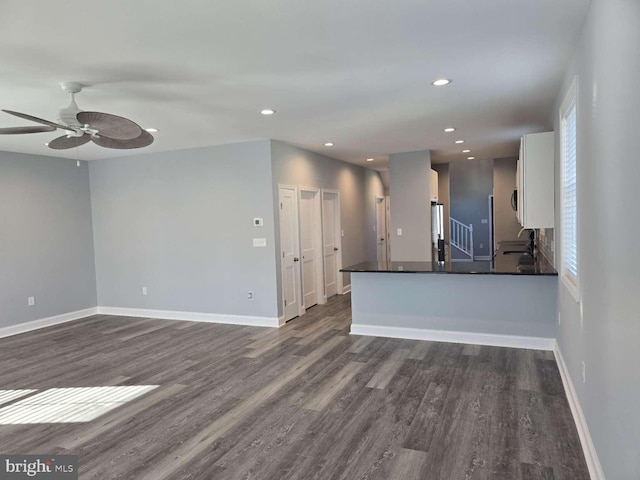 unfurnished living room featuring ceiling fan, dark hardwood / wood-style flooring, and sink