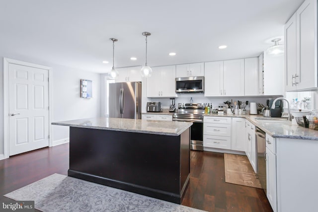 kitchen featuring appliances with stainless steel finishes, white cabinetry, a kitchen island, and sink