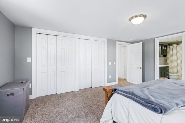 bedroom with carpet flooring, connected bathroom, and two closets