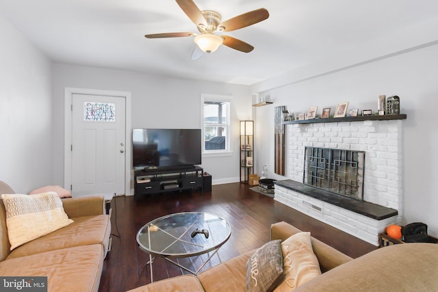 living room with a brick fireplace, ceiling fan, and dark wood-type flooring