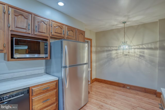 kitchen featuring light wood-type flooring, stainless steel appliances, and hanging light fixtures