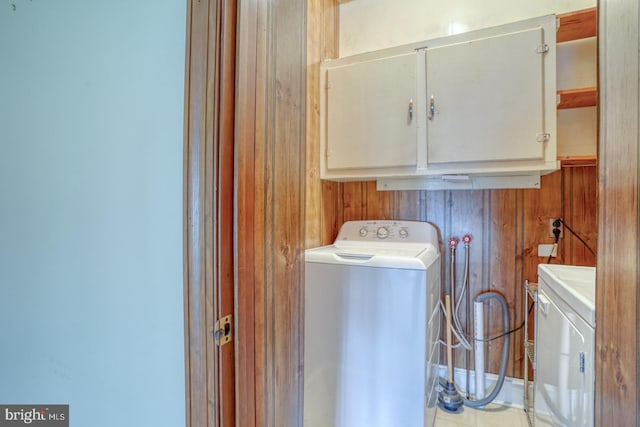 washroom with washer / clothes dryer, wooden walls, and cabinets