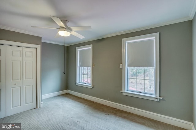 unfurnished bedroom featuring ceiling fan, light colored carpet, ornamental molding, and a closet