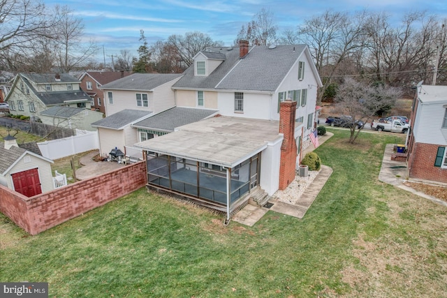 back of property with a lawn and a sunroom