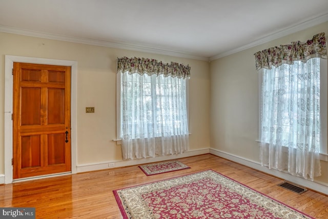 entrance foyer with ornamental molding and light hardwood / wood-style flooring