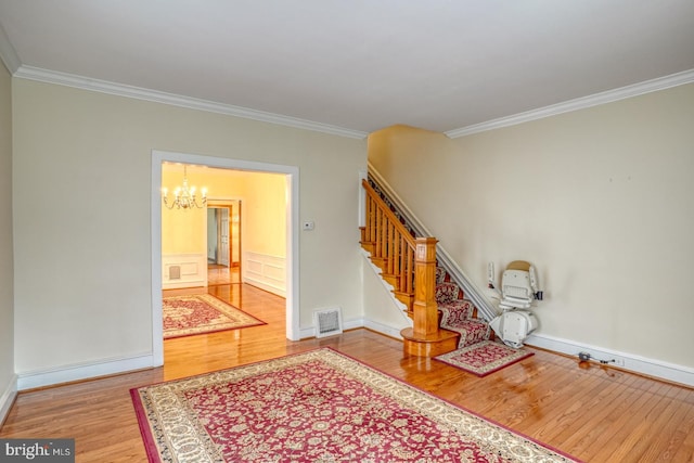 interior space featuring a notable chandelier, wood-type flooring, and crown molding