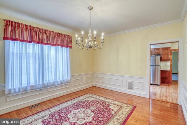 unfurnished room with hardwood / wood-style floors, an inviting chandelier, and ornamental molding