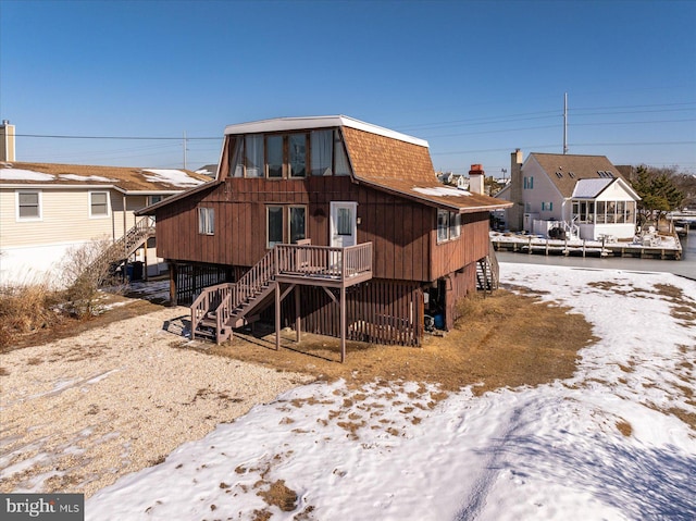 snow covered rear of property with a wooden deck