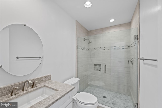 bathroom with toilet, a shower with door, and vanity