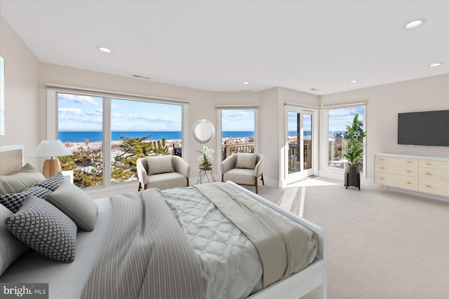 bedroom featuring access to exterior, light carpet, and a water view