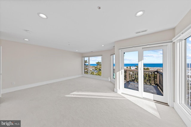 unfurnished living room featuring light carpet and a water view